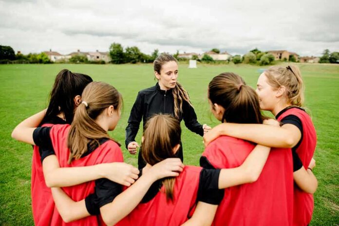 shutterstock_1236519469 Coach talks to youth team in a huddle on a field
