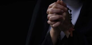 Hands clasped in prayer holding a rosary