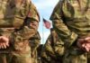 Unthinkable Pivot: U.S. Marine Becomes Somalia Power Broker Soldiers in camouflage stand with hands behind backs facing a U.S. flag
