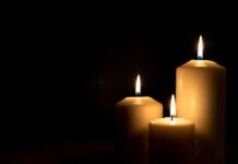 Three lit candles against a dark background