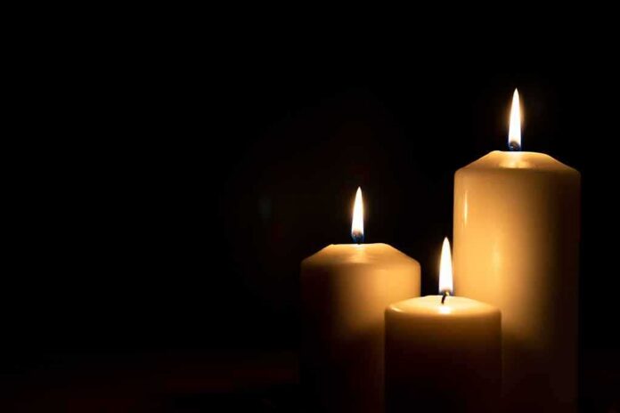 Three lit candles against a dark background
