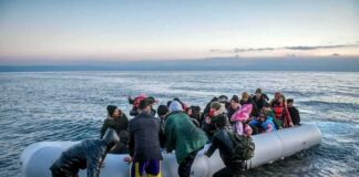 Group of people arriving on a crowded inflatable boat at a rocky shore