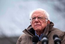 Nationwide AI Freeze? Bernie’s Crackdown Goes Nuclear elderly man in glasses speaking outdoors into microphones