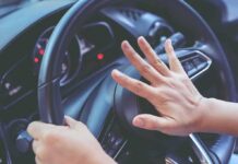 Driver pressing car horn on steering wheel