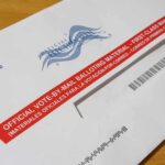 Ballot Chokepoint? USPS Quietly Flips the Switch Mail-in ballot envelope with red label on wooden table
