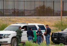 O’Hare Haul Stuns: Half-Ton Stimulant Nabbed law enforcement officers confer beside patrol vehicles near a border fence