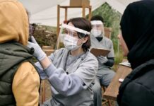 Healthcare worker in PPE examines a patient at an outdoor clinic