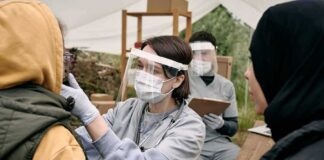 Healthcare worker in PPE examines a patient at an outdoor clinic