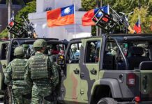 Logistics Nightmare – Taiwan’s Terrain Wrecks Invasion Dreams Soldiers beside camouflaged military vehicles with mounted guns and flags