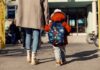 Child with backpack walking to school with adult
