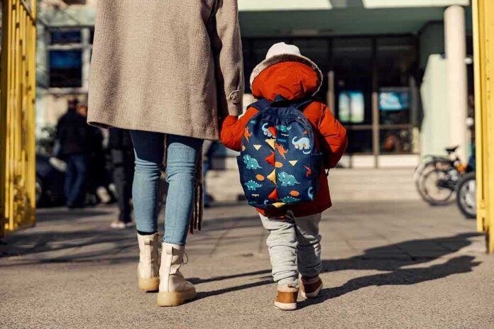 Child with backpack walking to school with adult