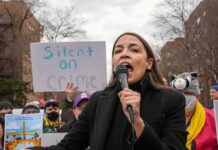 AOC’s Brand Backfires – Branded Toxic In Swing Seats woman speaking into a microphone at an outdoor protest