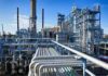 Industrial refinery with pipelines and distillation towers under blue sky