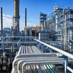 Industrial refinery with pipelines and distillation towers under blue sky