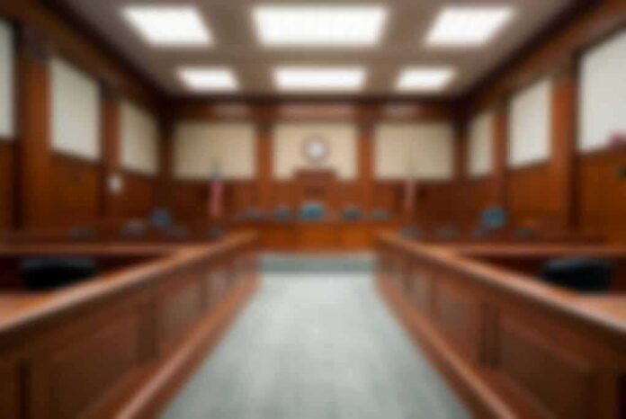 shutterstock_2324977165-1 Empty courtroom with wooden benches and judge's bench
