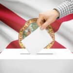 Florida Shock: Red Wall Tested – Cracks Or Mirage? Hand casting a ballot in front of the Florida state flag