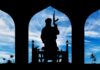 Blurred Labels, Deadly Blindspots: The Real Jihad Engine Silhouette of armed person standing before arches with mosque and palm trees at sunset sky