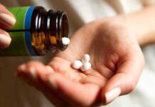 hand pouring white pills from a bottle