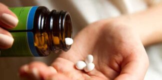 hand pouring white pills from a bottle