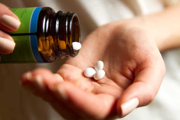 hand pouring white pills from a bottle