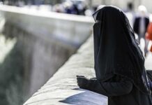 Classified Court Slams Alleged ISIS Matriarch Person in black veil leaning on a stone railing