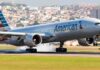 airliner landing on runway with smoke from tires