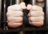 Tusk Targeted? Emergency Shields Go Up hands gripping prison bars