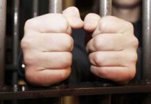 hands gripping prison bars