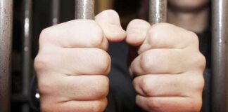 hands gripping prison bars