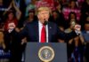Senator’s Defiant Texts Jolt MAGA Donald Trump speaking at a rally podium with arms raised
