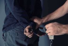 Porch Ambush Sparks 76-Count Bombshell person being handcuffed behind the back