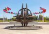 Kaliningrad Radar Puts NATO On Notice Metal sculpture with surrounding national flags in a plaza