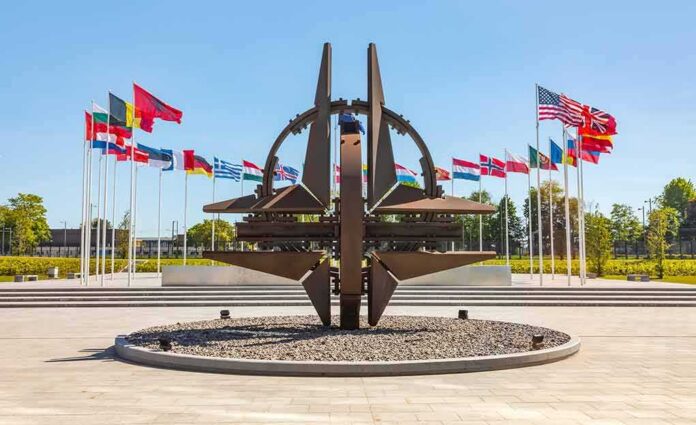 shutterstock_1399317884 Metal sculpture with surrounding national flags in a plaza