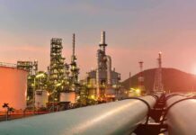 Energy Boom Shields America – Until 2026? Oil refinery with pipelines at sunset