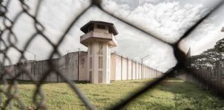 Prison watchtower behind chain-link fence