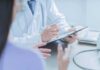 Doctor writing on clipboard during patient consultation