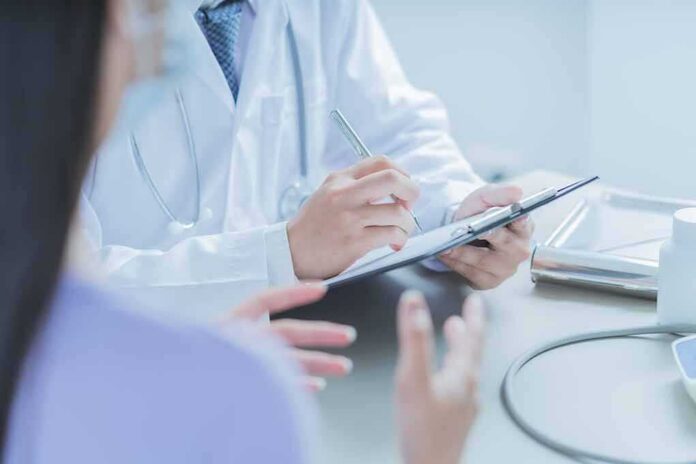 shutterstock_1706565550 Doctor writing on clipboard during patient consultation