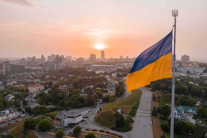 Ukrainian flag flying over a city at sunset