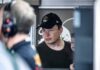 Elon Musk wearing a black cap in a crowded indoor setting