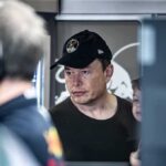 Elon Musk Turbocharges Red Ground Game Elon Musk wearing a black cap in a crowded indoor setting