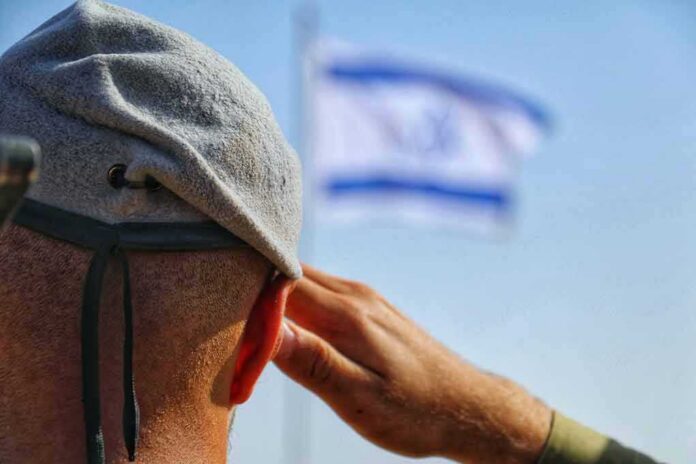 shutterstock_2335672235 Soldier saluting with a blurred flag in the background