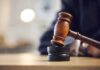 Judge's gavel striking a sound block on a wooden desk