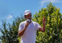 Ramaswamy’s $4M Grenade Hits Ohio Race Man in white shirt and cap speaking into a microphone outdoors