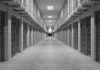 Prison corridor lined with barred cells on both sides