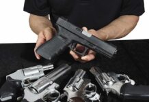 Person holding a black semi-automatic pistol over several revolvers