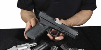 Person holding a black semi-automatic pistol over several revolvers