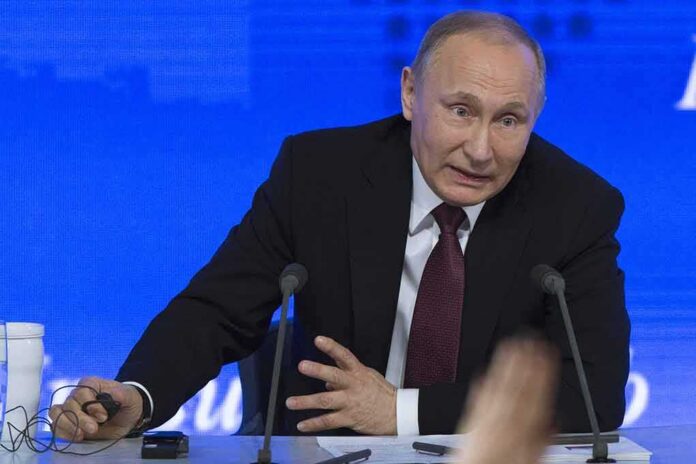 Vladimir Putin speaking at a press conference table with microphones