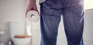 Person holding a toilet paper roll in a bathroom